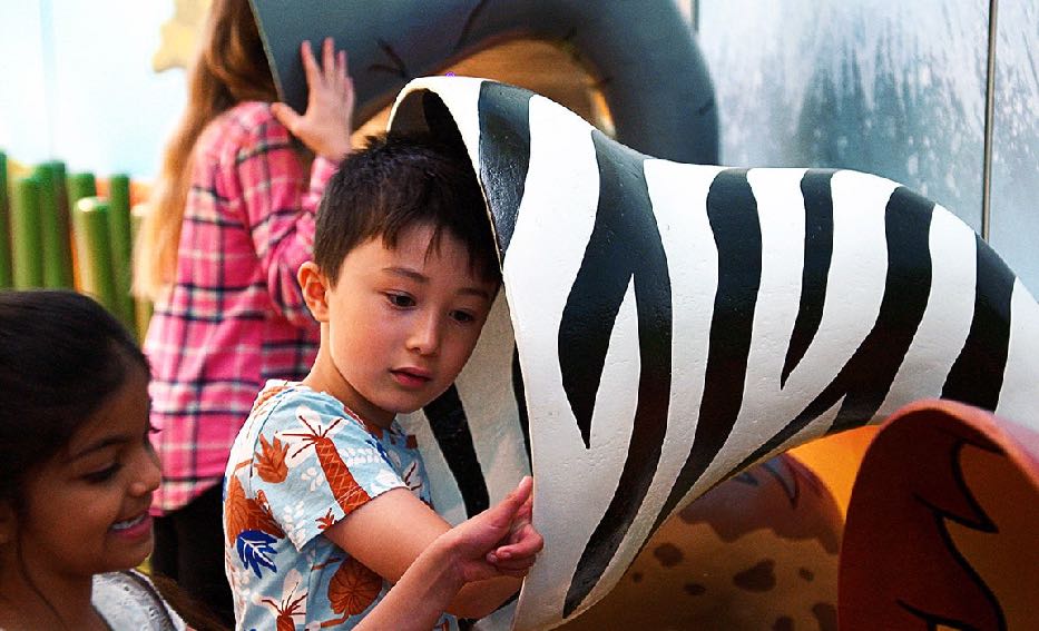 A child listening to the animals at the Imagination Tree installation